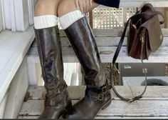 a woman sitting on the steps with her legs crossed wearing boots and holding a purse