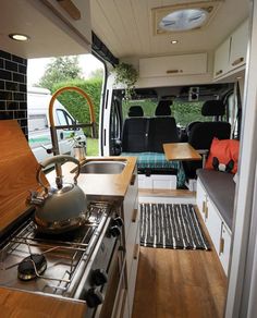 the interior of a camper van with an oven, sink and coffee pot on the stove