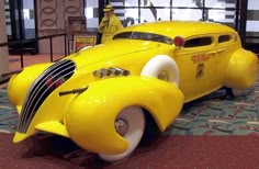 an antique yellow car is on display in a museum