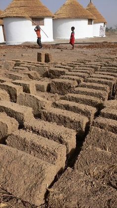 two people are standing in the middle of a maze made out of rocks and mud