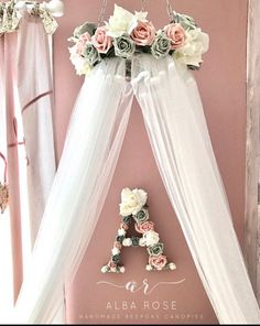 a white canopy bed with flowers hanging from it's sides and the letter e