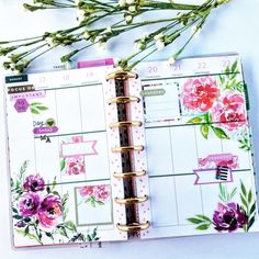 an open planner book with flowers on the cover and pink accents, sitting next to a bouquet of baby's breath buds