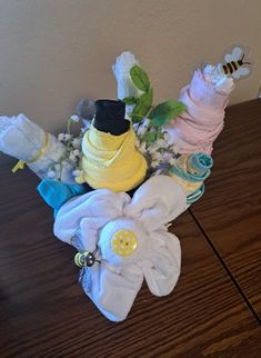 a bouquet of cloths and flowers sitting on a wooden table with a wall in the background