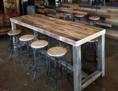 a wooden table with four stools next to it in a room filled with tables and chairs