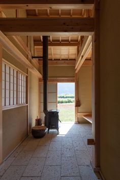 an empty room with a wood stove in the center and open doors leading to another room