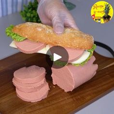 a person is holding a sandwich on a cutting board