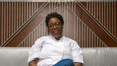 a woman sitting on top of a couch wearing glasses and a chef's coat