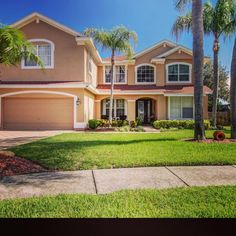 a house with palm trees in front of it and grass on the ground around it