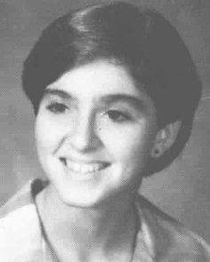 an old black and white photo of a woman smiling at the camera with her hair in a bun