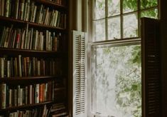 a bookshelf filled with lots of books next to a window