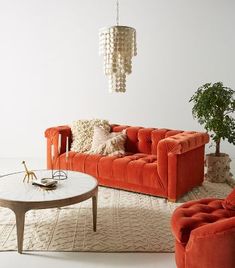 a living room with orange couches and white rugs on the floor next to a coffee table