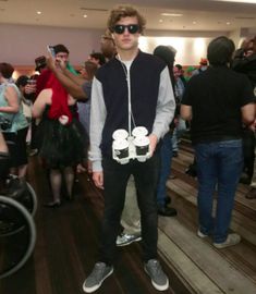 a young man standing in front of a group of people wearing sunglasses and sweaters