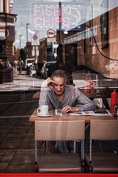 a man sitting at a table in front of a window