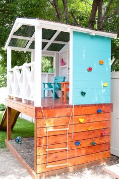 a small blue and white beach house with a slide in the back yard, next to a tree