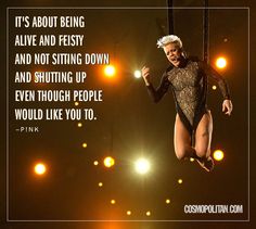 a woman is performing on stage with lights behind her and a quote about being alive and feisty