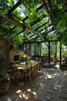 an outdoor dining area with glass walls and lots of greenery on the outside wall