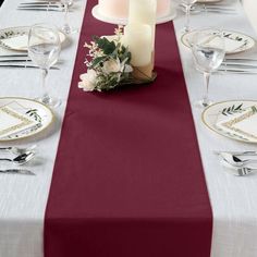 the table is set with white and red place settings, silverware, and candles