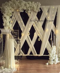 an elegant wedding setup with white flowers and chandeliers on the wall behind it