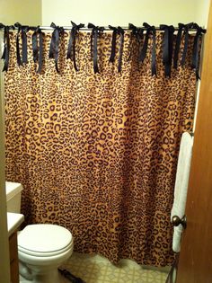 a leopard print shower curtain with black ribbon hanging from it's edge in a bathroom