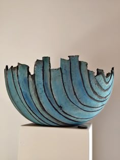 a blue bowl sitting on top of a white table next to a wall with a pink background