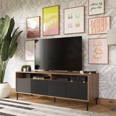 an entertainment center in a living room with art on the wall and a large television