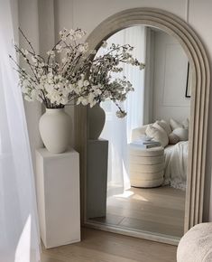 a vase filled with flowers sitting on top of a wooden floor next to a mirror