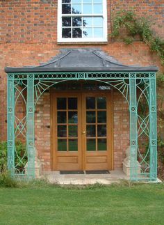 a green metal gazebo sitting in front of a brick building next to a window