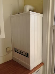 a white cabinet sitting on top of a wooden counter