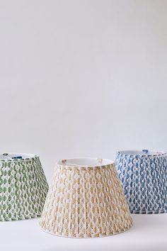 three lampshades in different colors and patterns on a white background, one with a light bulb