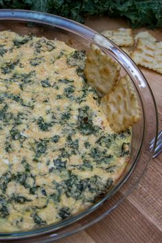 spinach dip in a glass bowl with crackers