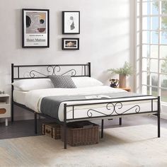 a bedroom with white walls and black iron bed frame in the middle, along with pictures on the wall