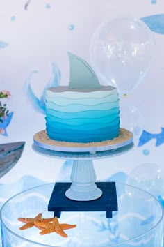 a blue and white cake sitting on top of a glass plate next to a starfish