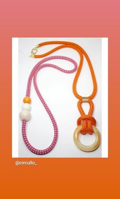 an orange and pink necklace with two rings on the front, one has a white bead