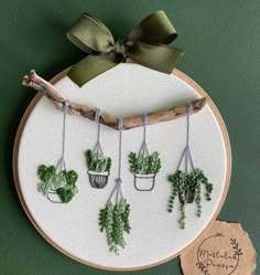 a cross stitch pattern with potted plants hanging on a branch and tied in twine