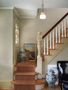 a staircase with vases and pictures on the floor in front of it's railing