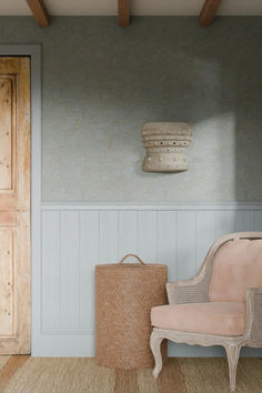 a chair and basket in a room with light blue walls, wood beams and wooden flooring