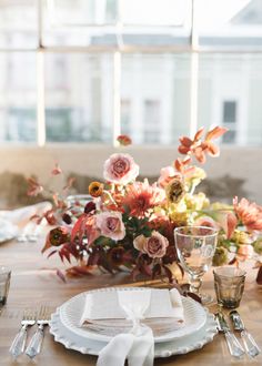 the table is set with white plates and silverware, napkins, and flowers