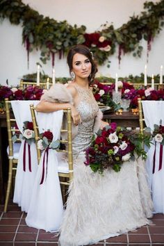 a woman sitting at a table with flowers and candles