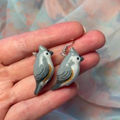 a pair of bird earrings sitting on someone's hand