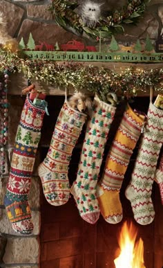 christmas stockings hanging from a mantel over a fireplace with a fire in the background