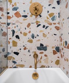 a bathtub with gold faucet and colorful tiles on the wall