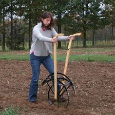 a woman standing in the middle of a field with a wooden pole attached to it