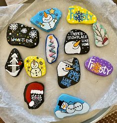 decorated rocks sitting on top of a plate with frosting and snowflakes around them