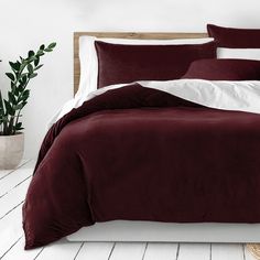 a bed with white sheets and maroon comforter