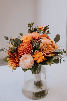 a vase filled with orange flowers and greenery