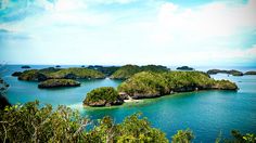 an island with several small islands in the middle of blue water surrounded by greenery