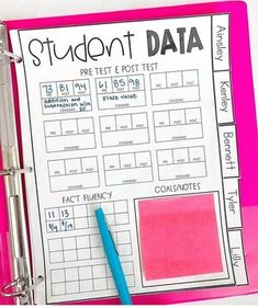 a pink binder with a blue pen on top of it and a student data book