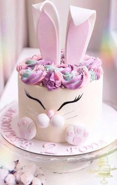 a white cake with pink frosting and bunny ears on top