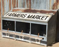 an old metal box with the words farmers market on it's side, sitting in front of a rusted wall