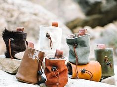 five different colored leather bags sitting on top of a rock